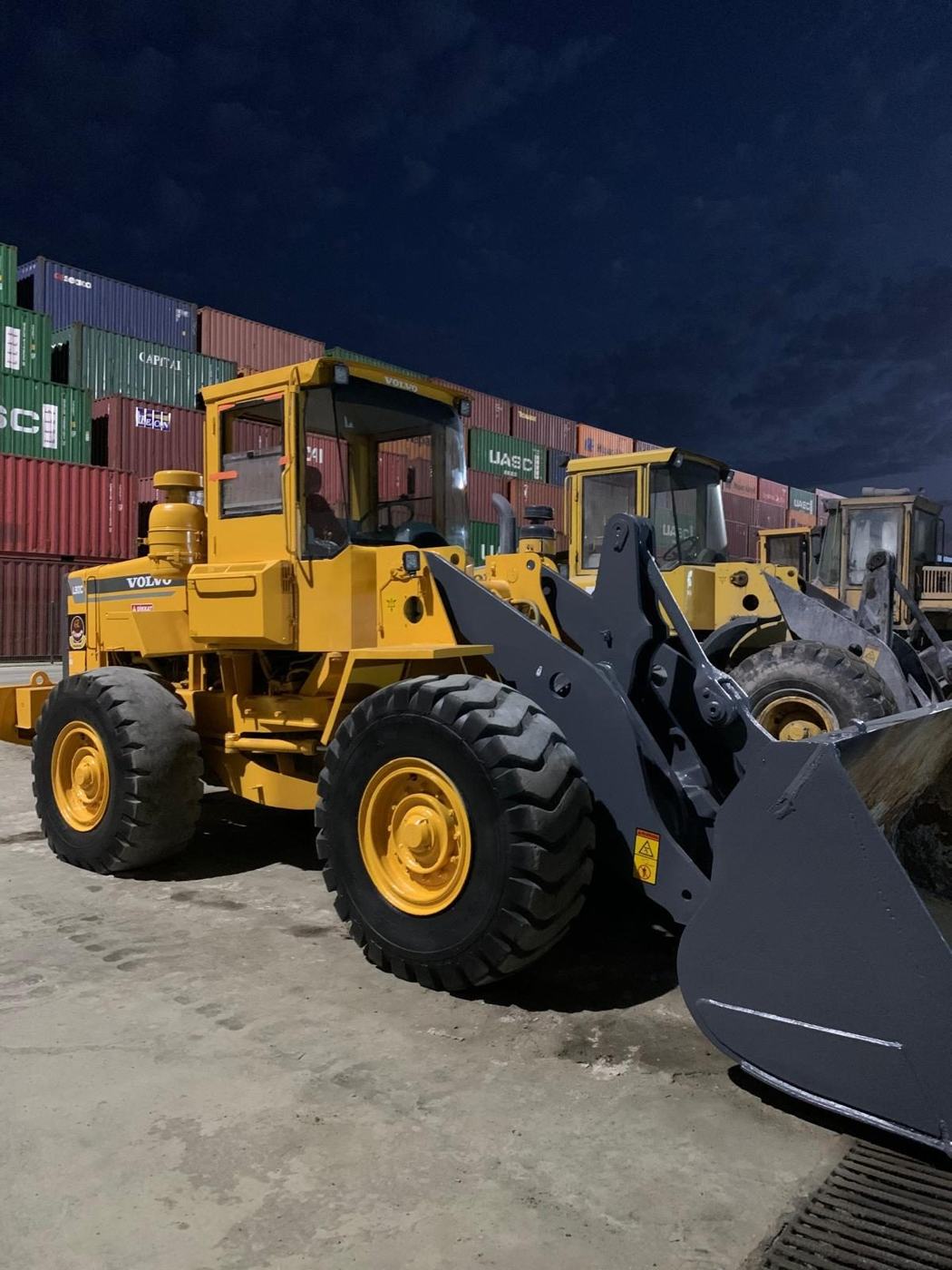Gece konteyner sahasında bakımlı Volvo yükleyiciler